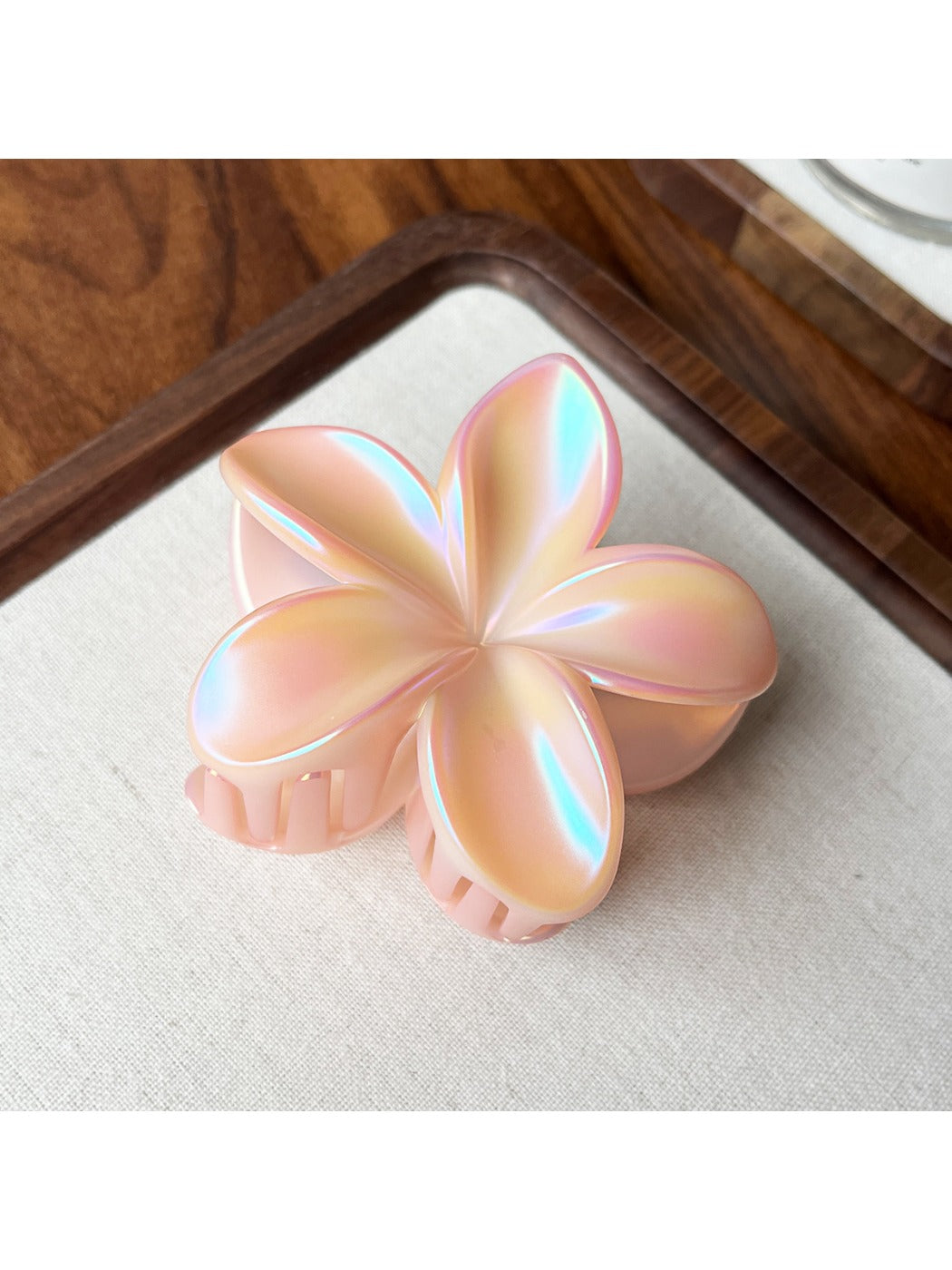 Beau flower shaped claw clip held between fingers showing grip