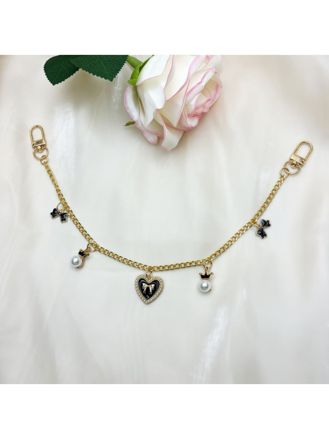 Side view of pink heart-shaped bag charm with gold bow and clasp