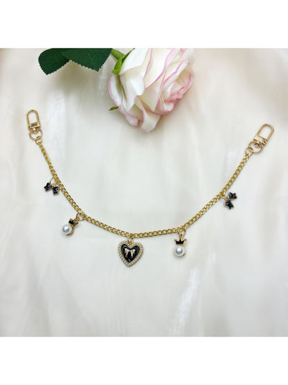Side view of pink heart-shaped bag charm with gold bow and clasp