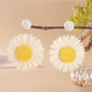 Raffia woven sunflower earrings resting on a wooden surface with natural light