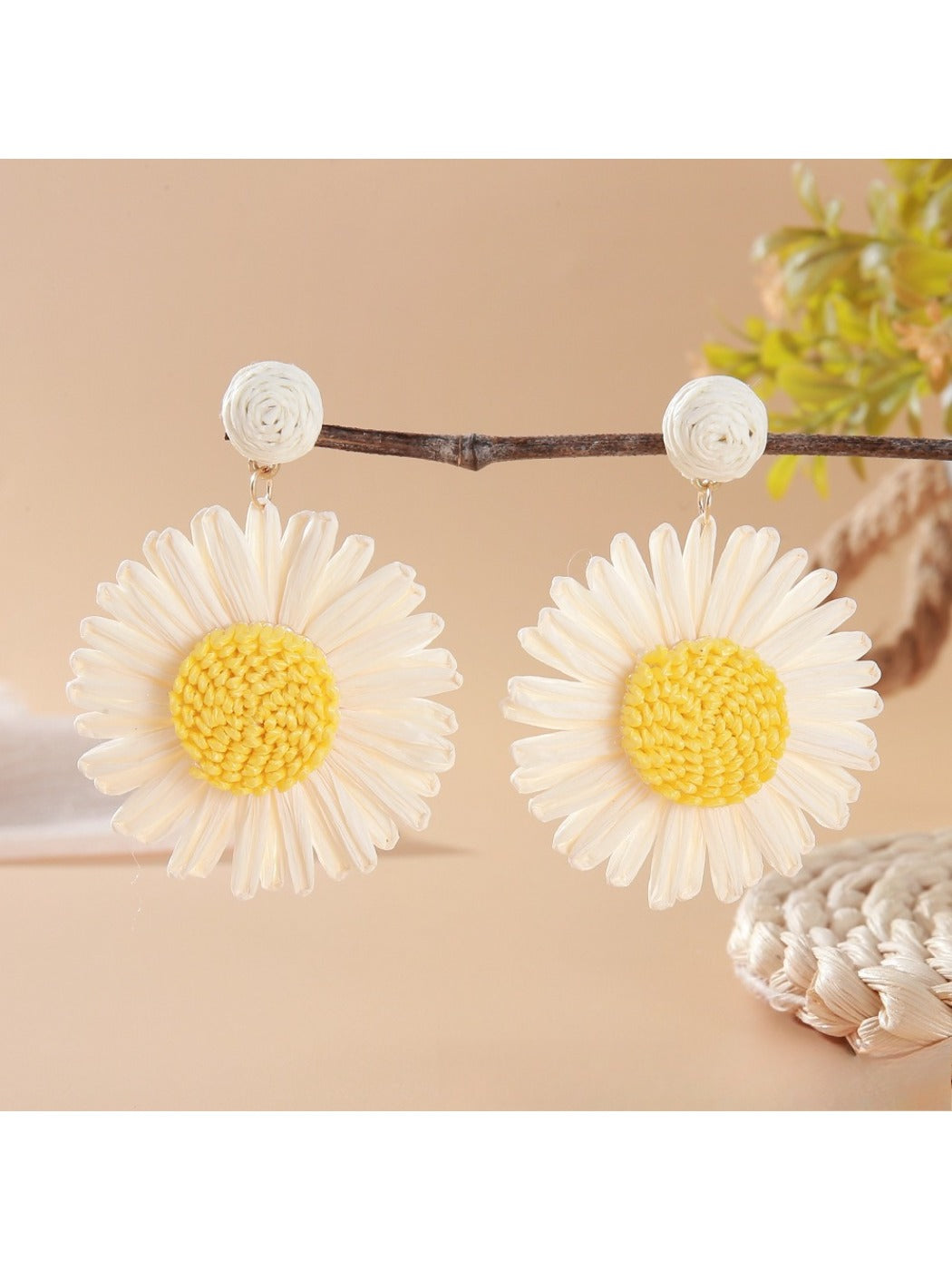 Raffia woven sunflower earrings resting on a wooden surface with natural light