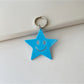 Silver star keychain placed next to a smartphone and wallet on a table