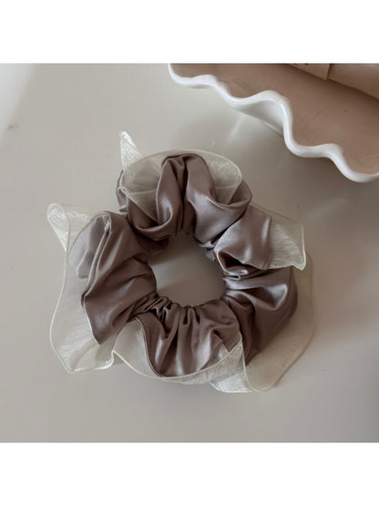 Glossy scrunchie wrapped around a ponytail in natural light