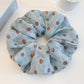 Gifty scrunchie styled on a wrist showing its gathered fabric design