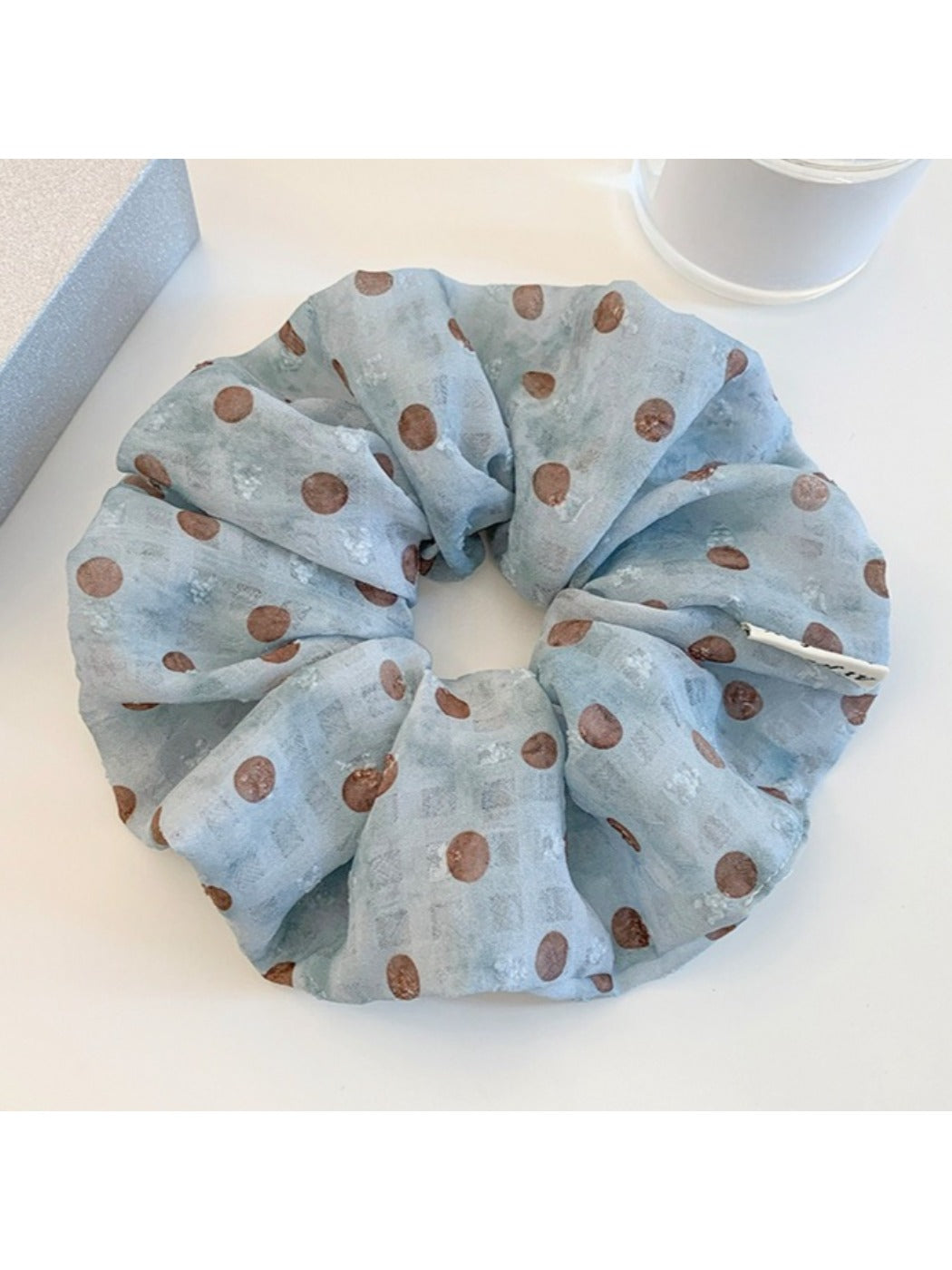 Gifty scrunchie styled on a wrist showing its gathered fabric design