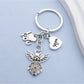 Alloy angel keychain hanging from a set of keys on a wooden surface