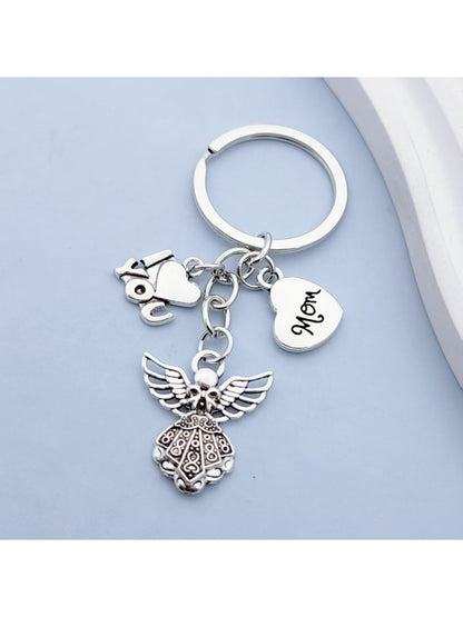 Alloy angel keychain hanging from a set of keys on a wooden surface