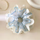 Close-up of blue fabric scrunchie featuring intricate lace edging