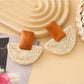 Top view of raffia mushroom shaped stud earrings highlighting woven details