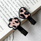 Beau hair clip held in hand displaying translucent acrylic material with flower and heart
