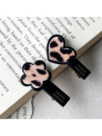 Beau hair clip held in hand displaying translucent acrylic material with flower and heart