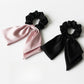 Satin bow hair tie styled on a model's blonde hair in a ponytail
