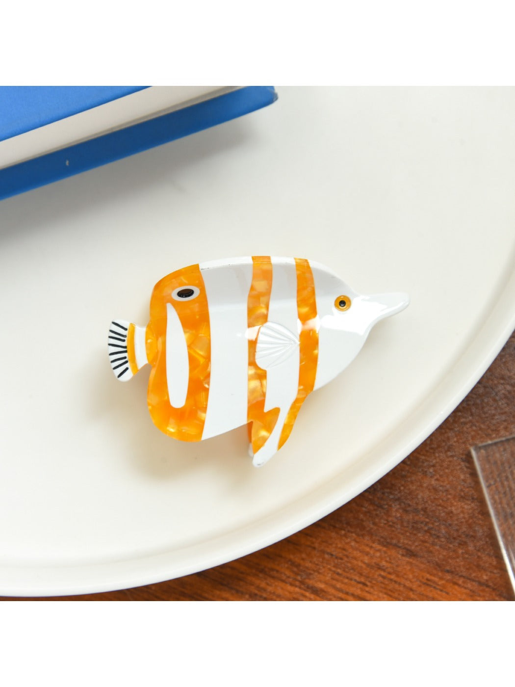 Beau tropical fish hair clip resting on wooden surface highlighting color contrast