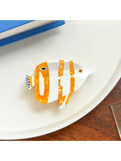 Beau tropical fish hair clip resting on wooden surface highlighting color contrast