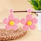 Model holding earedge knitted flower earrings near her ear