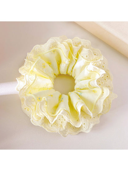 Yellow ruffle scrunchie worn in a ponytail on a model with brown hair