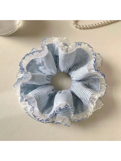 Navy blue scrunchie with retro white and light blue stripes on a white background