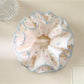Pink scrunchie with multicolored polka dots displayed on white background