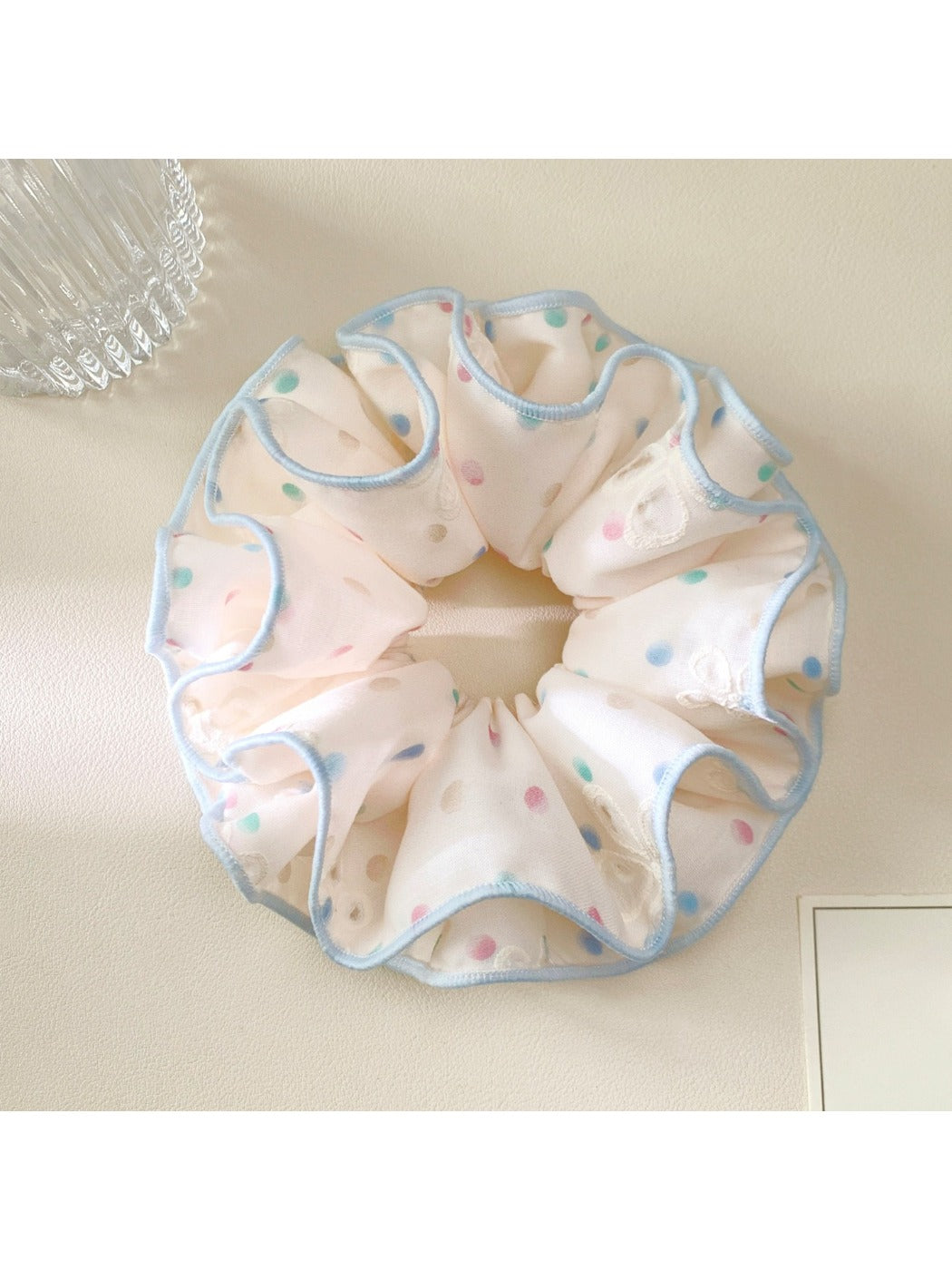 Pink scrunchie with multicolored polka dots displayed on white background