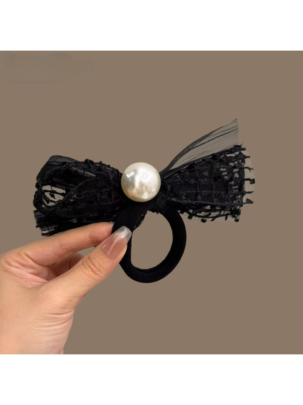 Side view of the black hair tie featuring a decorative bow with pearl accents