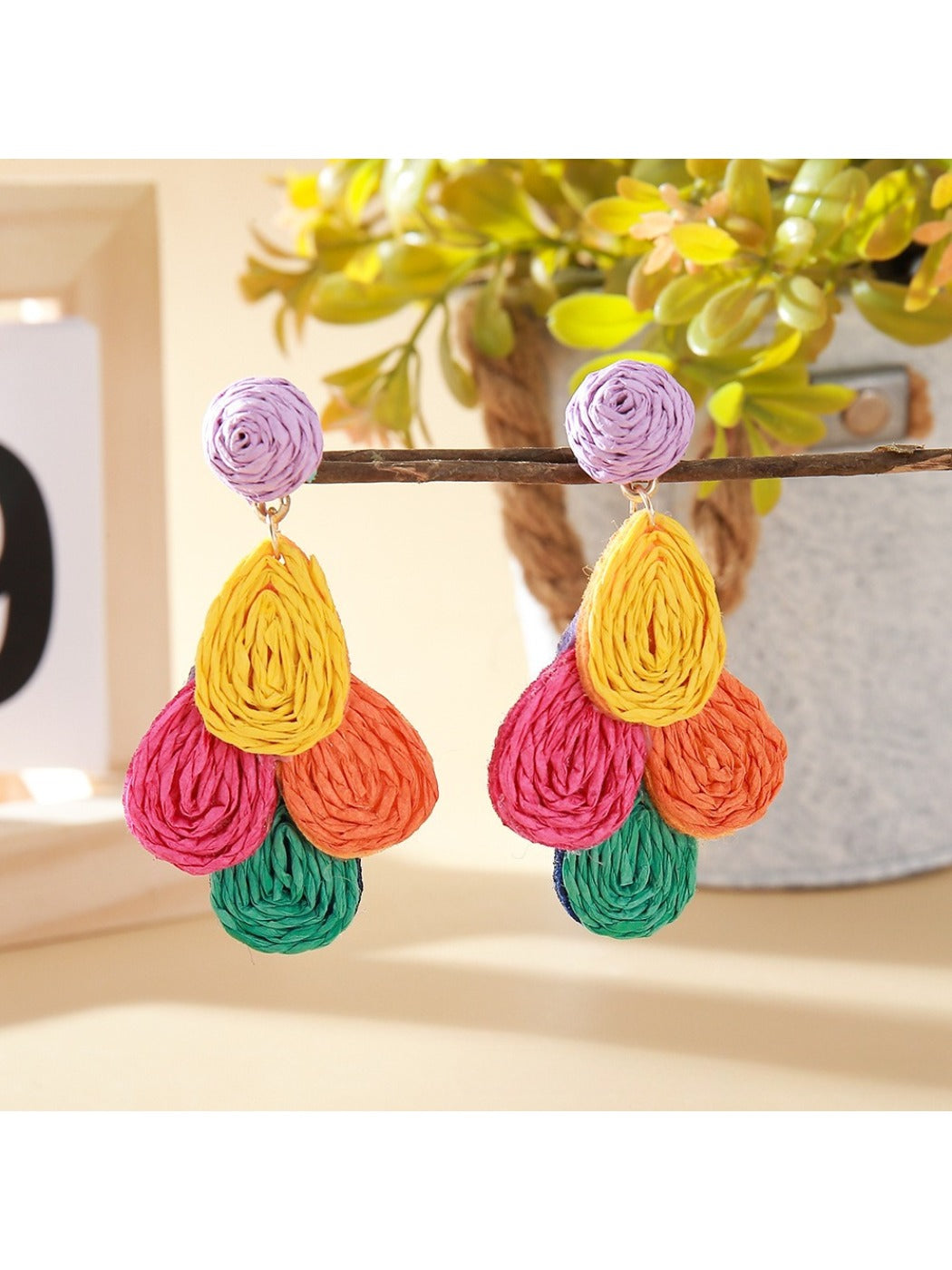 Earedge raffia drop earrings displayed on a wooden stand with natural lighting