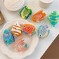 Beau colorful fish shaped claw clip with blue and orange details on white background