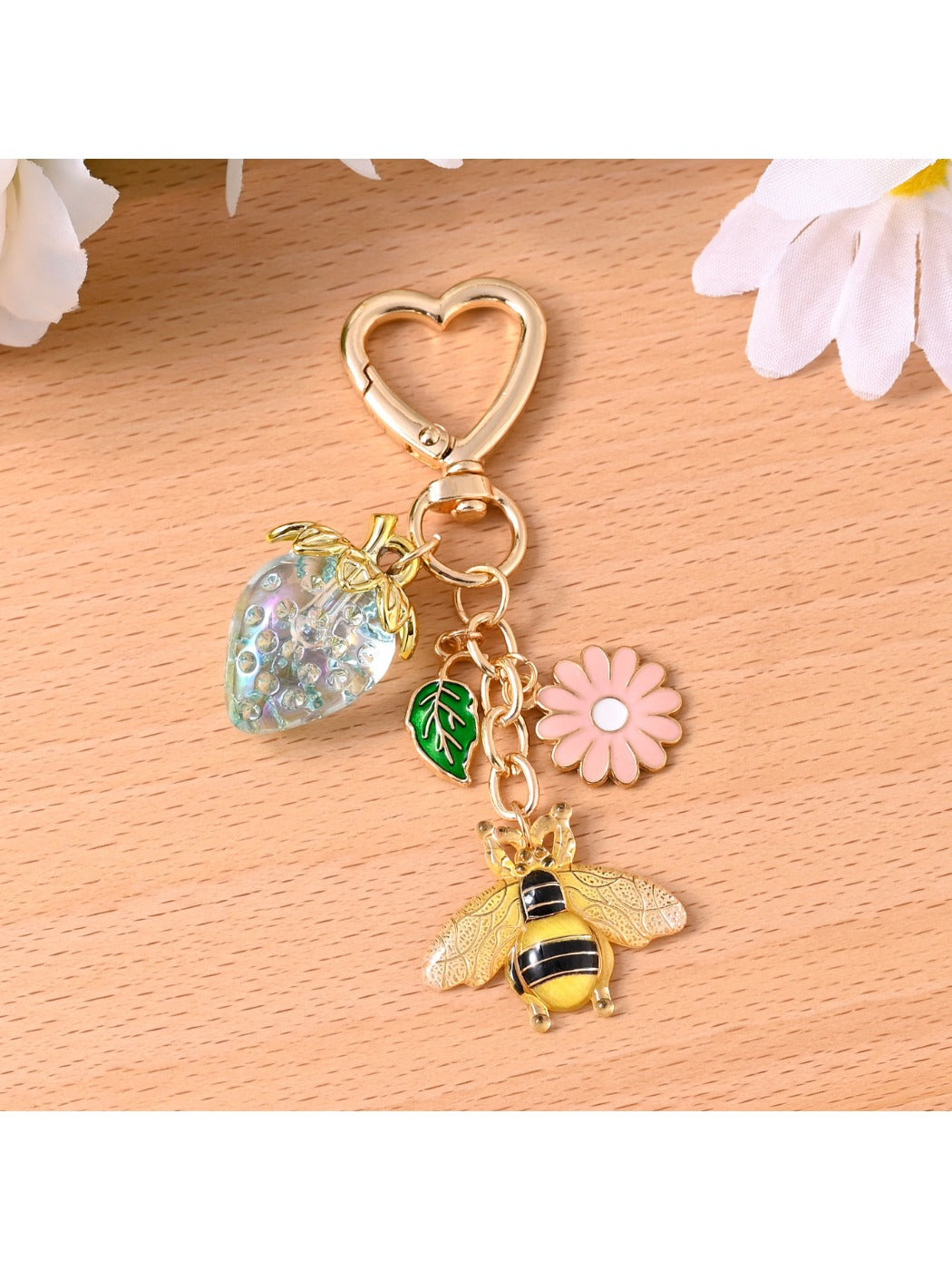 Gold bee keychain attached to a set of keys on a wooden surface