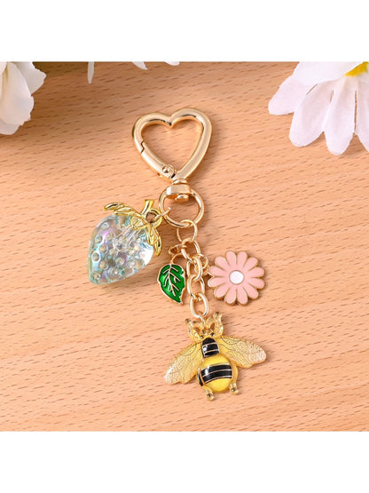 Gold bee keychain attached to a set of keys on a wooden surface