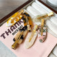 Side view of Beau acetate invisible hair clip displaying metal spring mechanism