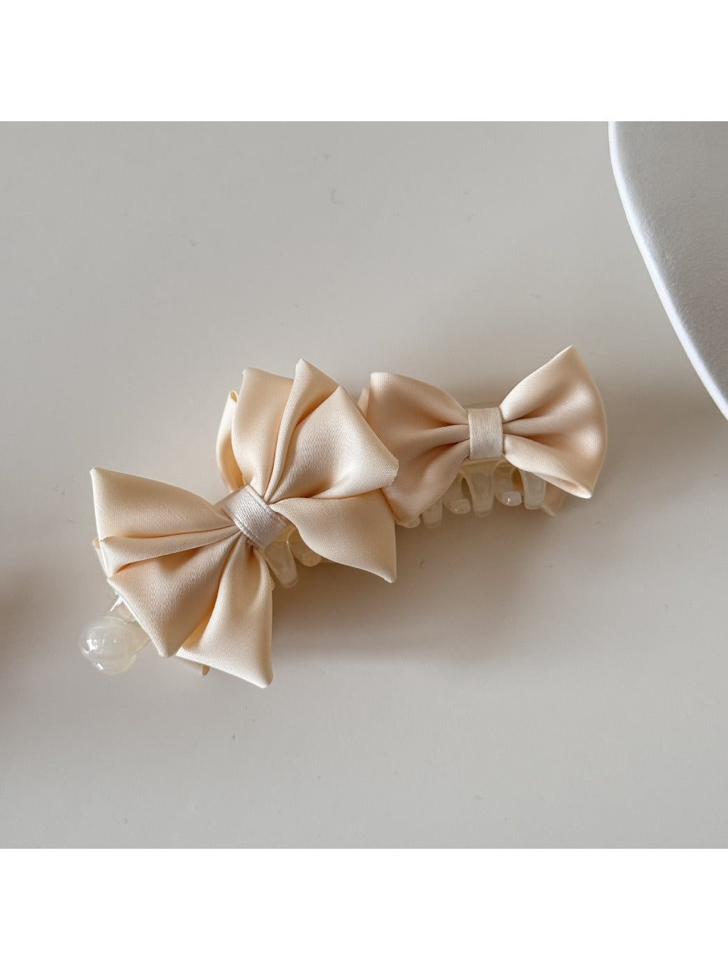 Beau satin bow banana clip held in hand showing size and shape