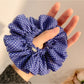 Black and white polka dot scrunchie displayed on a white background