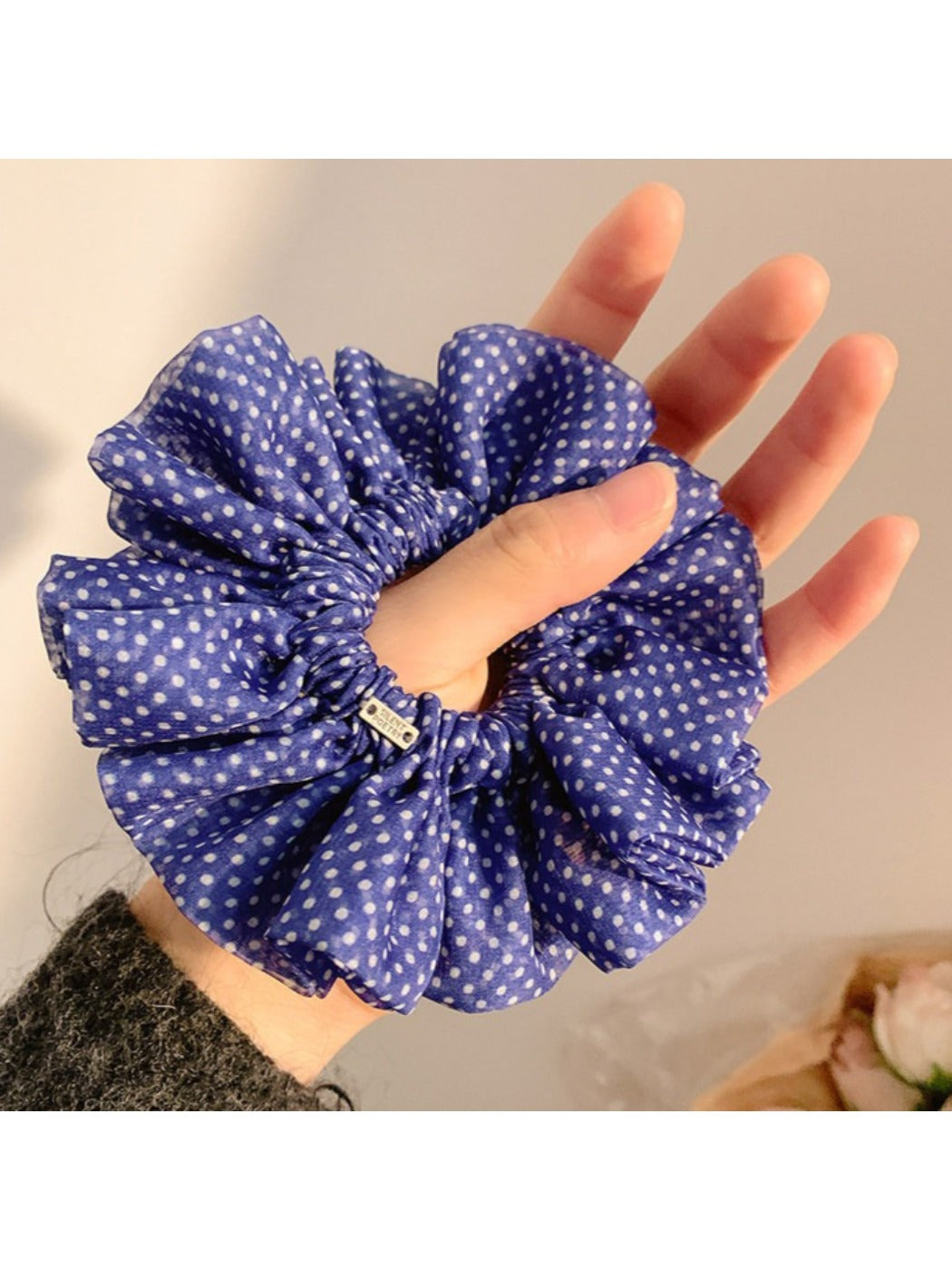 Black and white polka dot scrunchie displayed on a white background