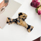 Beau minimalist bow shaped claw clip in matte black next to matching accessories