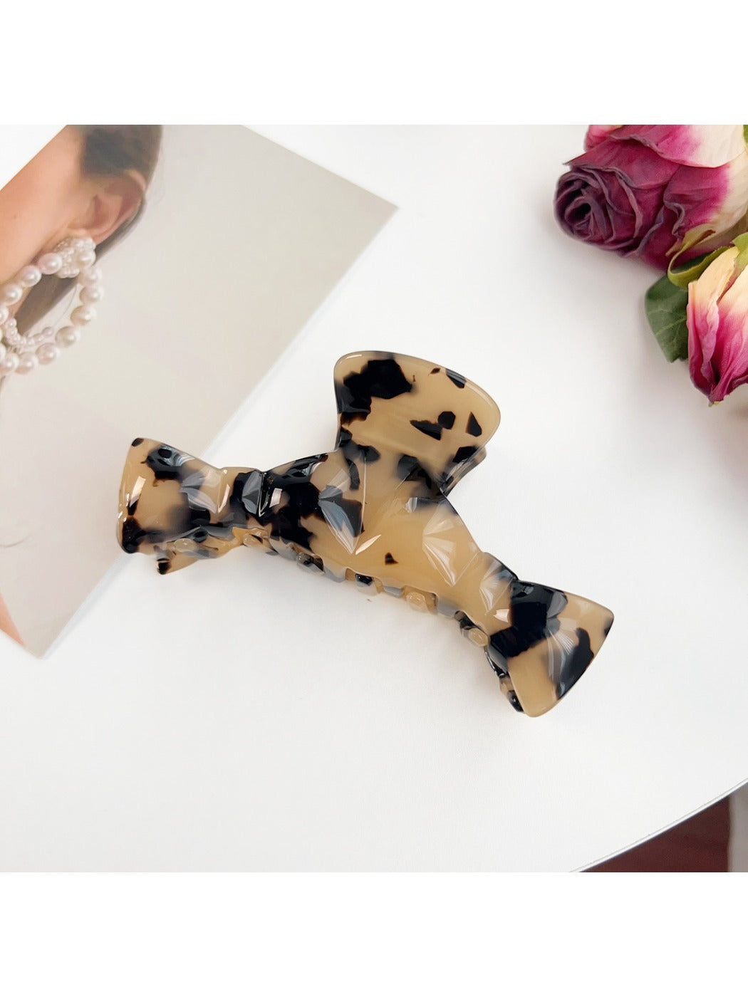 Beau minimalist bow shaped claw clip in matte black next to matching accessories