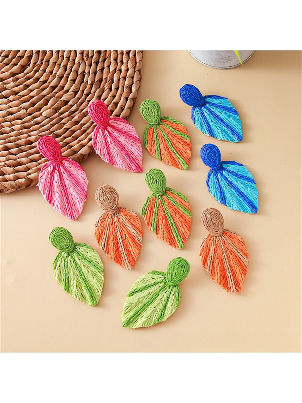 Close-up of Earedge raffia woven leaf shaped earrings on white background