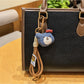 Bear charm keychain next to a smartphone on a desk