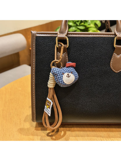 Bear charm keychain next to a smartphone on a desk