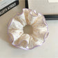 Close-up of purple fabric scrunchie featuring white polka dots