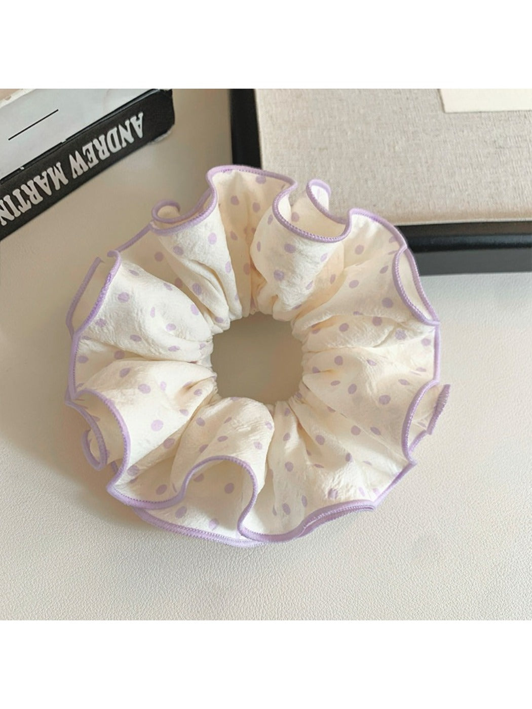 Close-up of purple fabric scrunchie featuring white polka dots