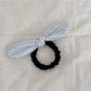 Gifty hair tie with red bow and plaid design held in hand against a neutral background