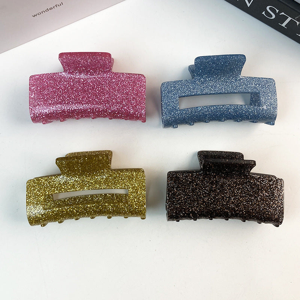 Four glitter rectangular hair claws arranged on a white surface