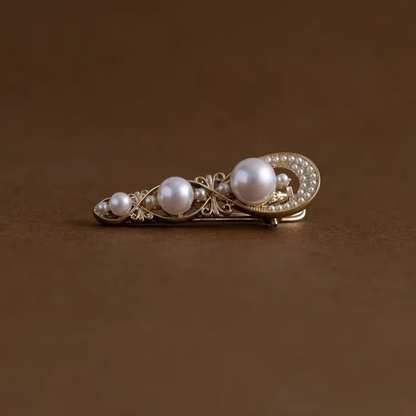 Gold-tone hair clip with three graduated white beads, low front view