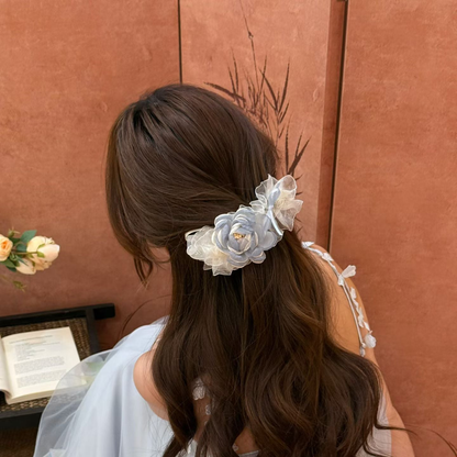 Blue floral hair claw with layered flowers and gathered trim on a low ponytail