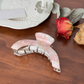 Pink and white mottled crescent-shaped hair claw, side view