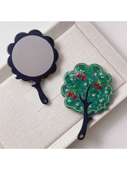 Mirroray handheld mirror with tree-shaped frame next to decorative items