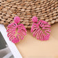 Earedge raffia woven hollow leaf shaped earrings displayed with natural decor