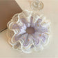 Purple ruched scrunchie displayed on a white background showing texture