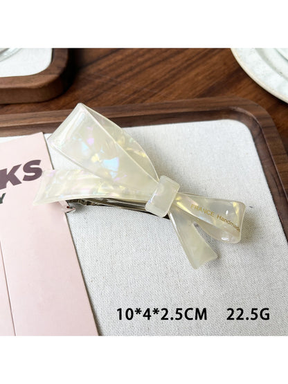 Beau acetate bow hair clip placed on wooden surface with natural light