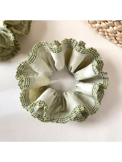 Close-up of delicate green double layer scrunchie with soft fabric texture