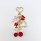 Cherry bow charm keychain attached to a set of keys with a blurred background